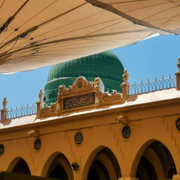 Green dome, mosque, architectural details, clear sky.